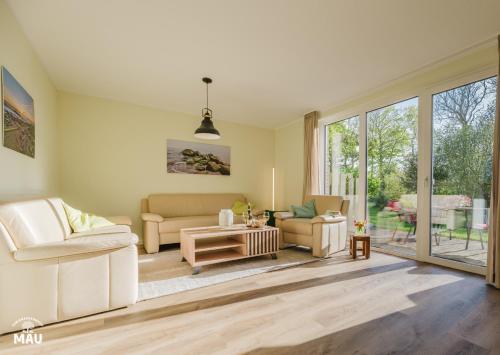 a living room with white furniture and large windows at Ferienbauernhof Mau in Fehmarn