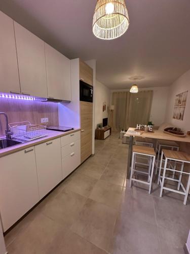 une grande cuisine avec des armoires blanches et une table dans l'établissement A 500m de la plage - L Oyat -, à Mimizan-Plage