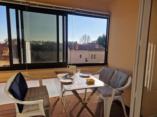 un tavolo e delle sedie in una stanza con una grande finestra di T2 avec grand balcon filant, Wifi, Clim à 4 min Remparts ad Avignone