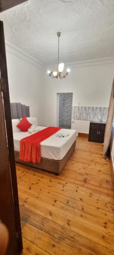 Un dormitorio con una cama grande con una manta roja. en Neo & Ruks Guest House Boston Belleville 7, en Bellville
