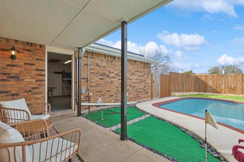 a swimming pool with a green lawn next to a house at Charming 3Bd 2Ba Home with Private Pool in The Colony