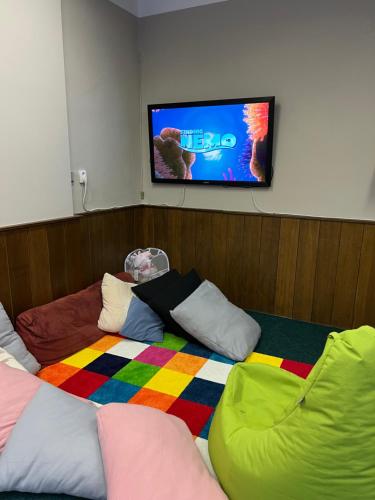 a room with a bed with colorful pillows and a flat screen tv at Horský Hotel Jelínek in Bedřichov