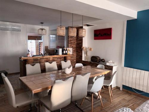 une salle à manger avec une table en bois et des chaises blanches dans l'établissement Maison face à l'océan classé 3 étoiles, à Montalivet-les-Bains