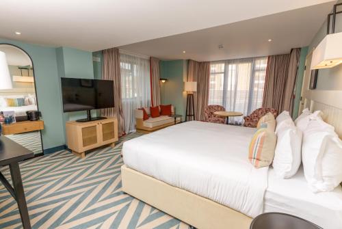 a hotel room with a bed and a flat screen tv at The Relais Cooden Beach and Spa in Bexhill