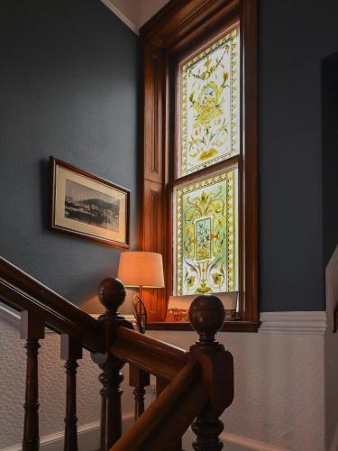 a staircase with a stained glass window and a lamp at MacKays in Oban