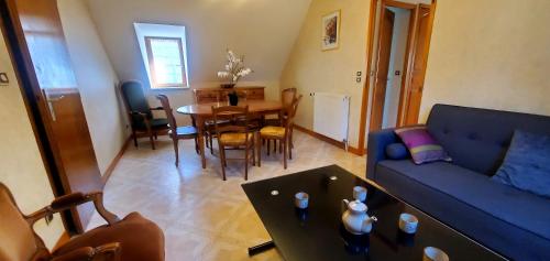 a living room with a blue couch and a table at Le logis de l'Ajolaise in Vielle-Aure