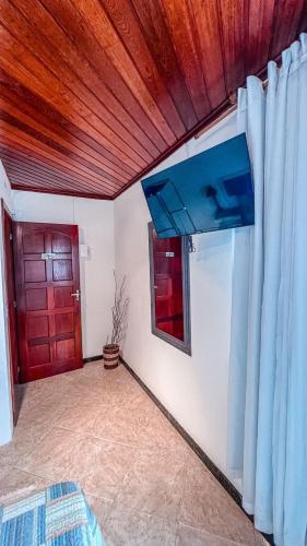a room with a red door and a wooden ceiling at Flat - Studio - Casas Arraial Só Lazer in Arraial do Cabo