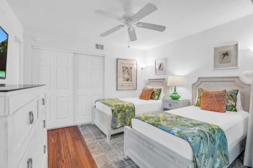 a white bedroom with two beds and a ceiling fan at Corner Unit Updated And Near Lobby in Naples
