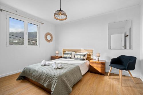 una camera da letto bianca con un letto e una sedia di Petit Campanário a Campanário