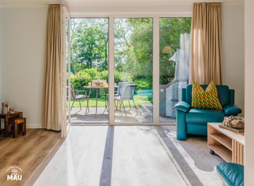 a living room with a blue couch and a sliding glass door at Ferienbauernhof Mau in Fehmarn