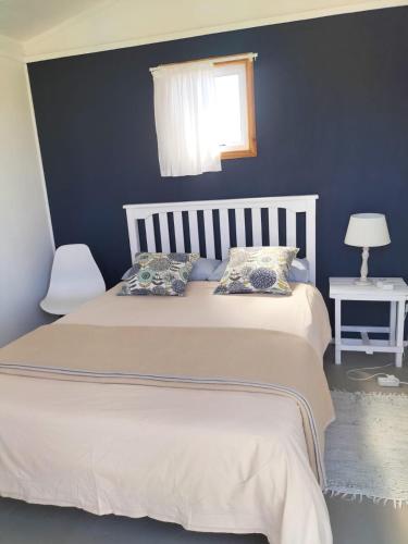 a bedroom with a white bed with a blue wall at Townsend Backpackers in Lambertʼs Bay