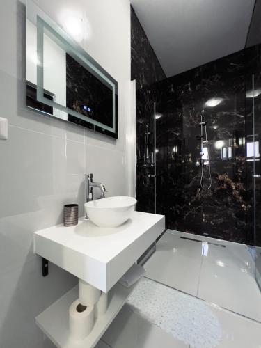 a white bathroom with a sink and a shower at Chalet 173 in Gura Humorului