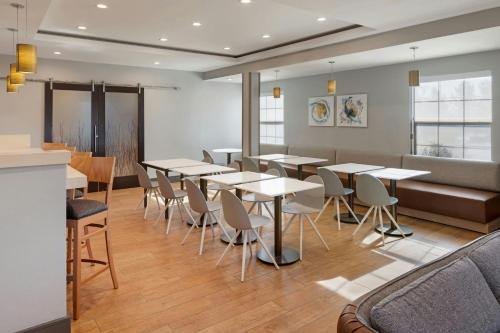 a dining room with tables and chairs and a couch at TownePlace Suites by Marriott Ontario Airport in Rancho Cucamonga