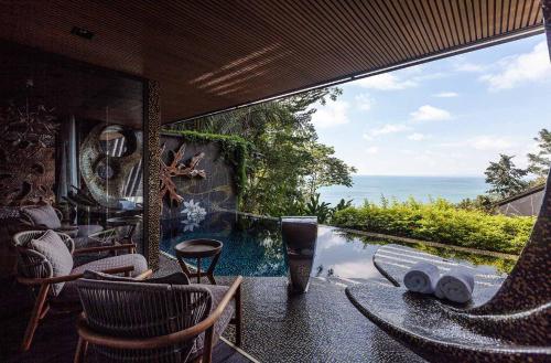 a patio with a pool and chairs and the ocean at Makanda by The Sea Hotel Adults Only in Manuel Antonio