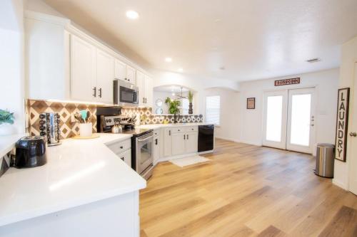 a large kitchen with white cabinets and wooden floors at Big Family House w Theater Pool table in San Antonio