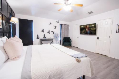 a bedroom with a white bed with a ceiling fan at Big Family House w Theater Pool table in San Antonio