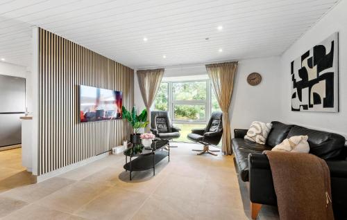 a living room with a black leather couch and chairs at 5 Bedroom Nice Home In Blåvand in Blåvand