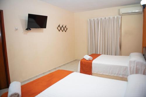 a hotel room with two beds and a tv at Hotel Uxulkah in Campeche