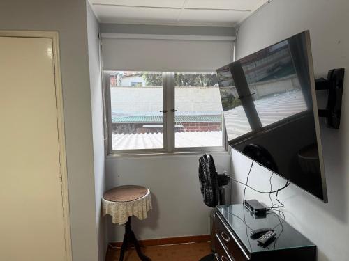 a room with a window and a stool and a television at Casa hotel la 33 in Medellín