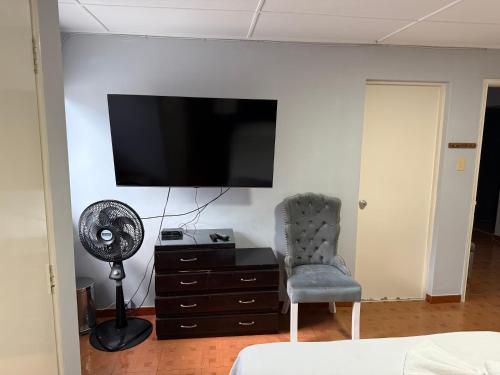 a room with a tv and a chair and a fan at Casa hotel la 33 in Medellín