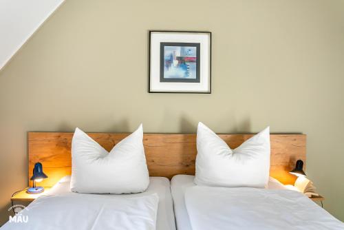 two beds with white pillows in a room at Ferienbauernhof Mau in Fehmarn