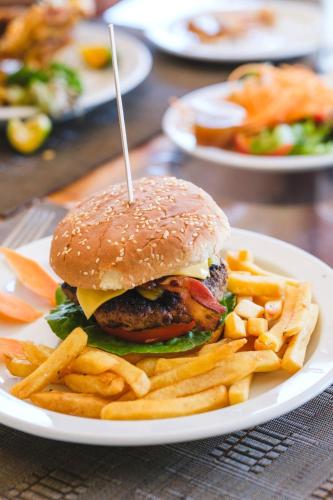 a plate with a hamburger and french fries on a table at Las Olas Beach Resort in La Barqueta
