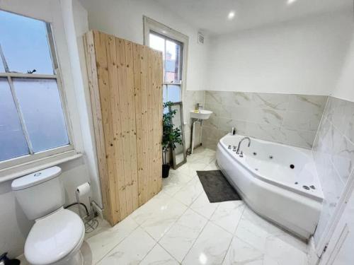 a bathroom with a tub and a toilet and a sink at Grand Vintage Home with Sauna & Style in Kirby Muxloe