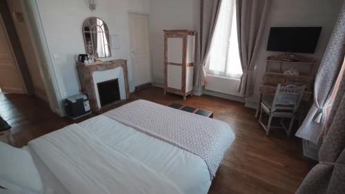 a bedroom with a white bed and a fireplace at Moulin d'Amour in Chambon