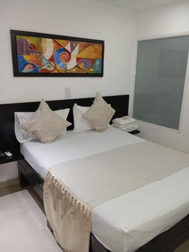 two beds in a room with white sheets and pillows at Hotel Plaza Norte Cali in Cali
