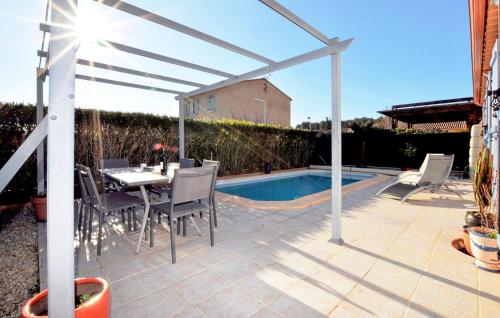 un patio avec une table et des chaises à côté d'une piscine dans l'établissement Nice Home In Lézignan-Corbières, à Lézignan-Corbières