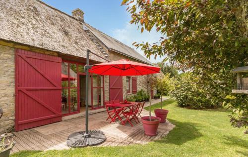 une terrasse avec un parasol rouge, une table et des chaises dans l'établissement Cozy Home In Saint Lyphard With Wifi, à Saint-Lyphard