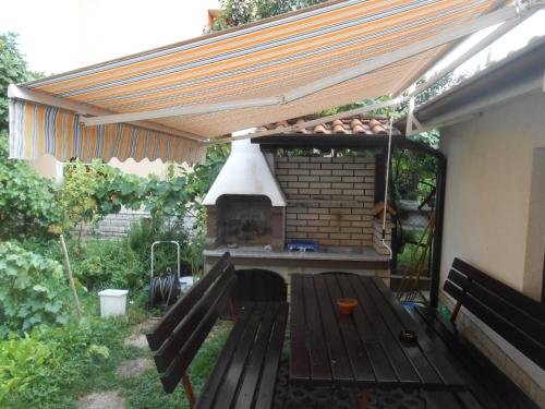 a barbecue under awning with a picnic table in a backyard at Love 2 Solkan in Nova Gorica