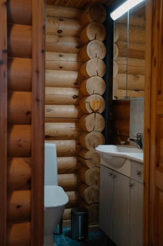 a bathroom with a toilet and a sink and wooden walls at Kiilopää Lodge Lapland Cabin in Kakslauttanen
