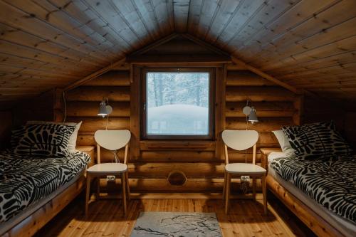two beds in a log cabin with a window at Kiilopää Lodge Lapland Cabin in Kakslauttanen