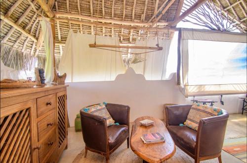 a room with two chairs and a table and a table at HUHURU House in Watamu