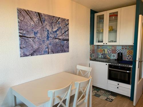 une cuisine avec une table et des chaises ainsi qu'une peinture murale. dans l'établissement Studio pieds des pistes les orres 1650, aux Orres