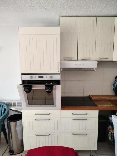 une cuisine avec des armoires blanches et un four à plaques de cuisson dans l'établissement Résidence Sda F2-merlette - deux pièces 6 pers au soleil des alpes expo SUD-OUEST MAE-5751, à Orcières