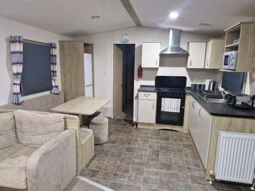 a kitchen and living room with a couch and a table at Highfield Grange Holiday Park in Clacton-on-Sea