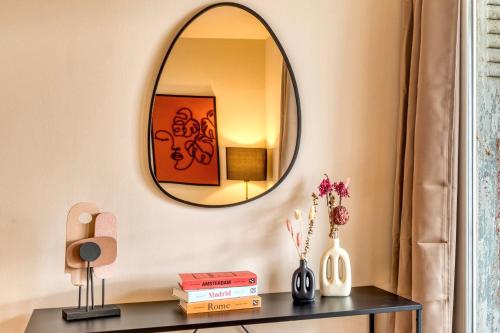 un miroir sur un mur au-dessus d'une table avec des livres dans l'établissement Le Panoramique - Grand T2 métro B Oullins, à Oullins