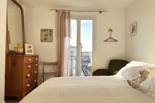 - un ours en peluche assis sur un lit dans une chambre dans l'établissement Le Mandela - Centre Historique Perret, au Havre