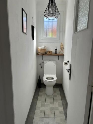 a bathroom with a white toilet with a window at Appartement spacieux in Jurançon