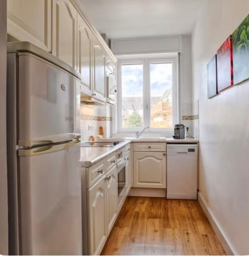  La cuisine est équipée de placards blancs et d'un réfrigérateur. dans l'établissement Urban Lodge YourHostHelper, à Deauville