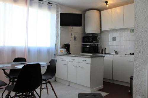 une cuisine avec des armoires blanches et une table avec des chaises dans l'établissement Appartement Studio PORT LA NOUVELLE PN480-074, à Port-la-Nouvelle