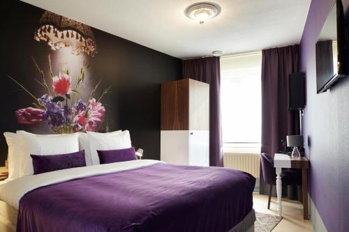 a bedroom with a purple bed with a flower painting on the wall at The Muse Amsterdam - Boutique Hotel in Amsterdam