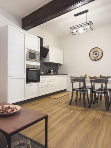 a kitchen with white cabinets and a dining table at Dimora Aimonetto in Pinerolo