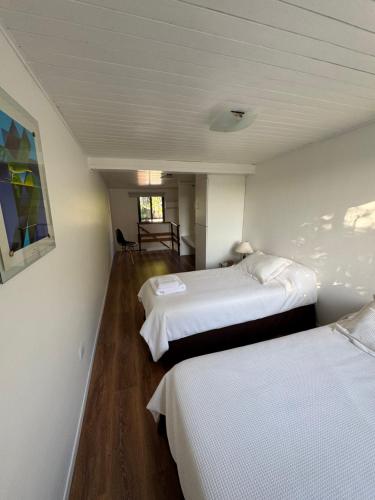 two beds in a room with white walls and wooden floors at Casi en Casa 2 in Lincoln