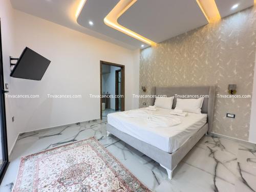 a bedroom with a bed with marble floors and a tv at Villa Radisson Vu de mer 2 in Mezraya