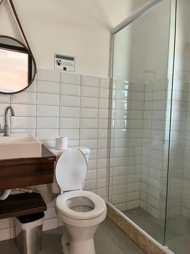 a bathroom with a toilet and a glass shower at Pousada Encanto dos Anjos in Búzios
