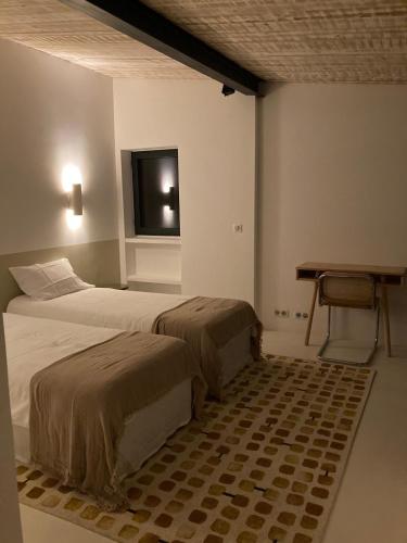 une chambre avec deux lits, un bureau et une télévision dans l'établissement Le Jardin des Graminées, à Cabrières-dʼAvignon