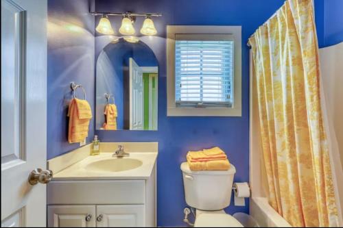 a blue bathroom with a toilet sink and a mirror at Bay Breeze - 3 Min Walk to Beach in Tybee Island